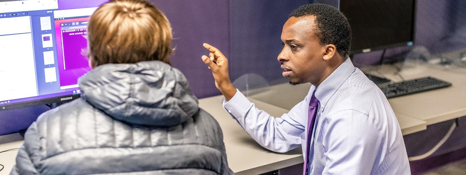 professor works with student on computer